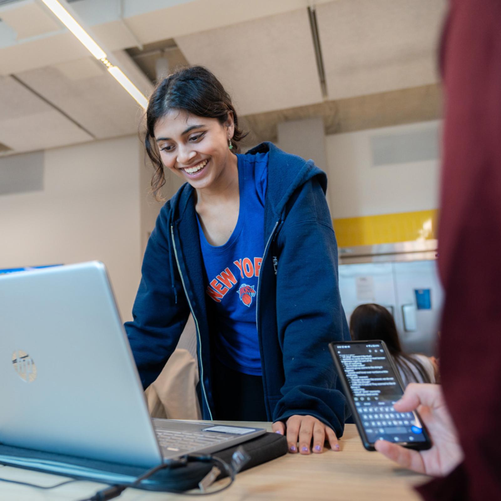 A female student leaning over her laptop at a table.