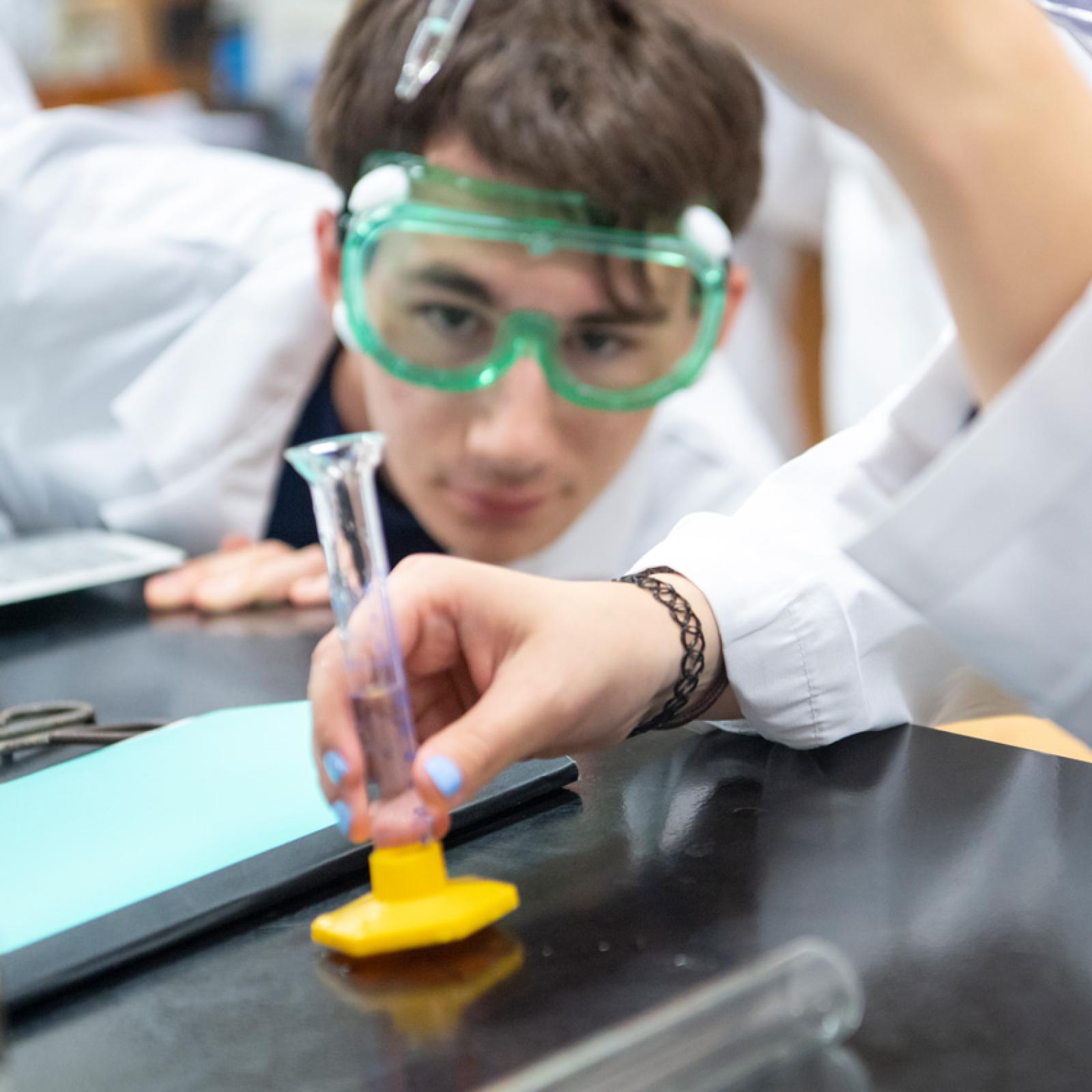 A Pace University student in a lab wearing safety goggles.