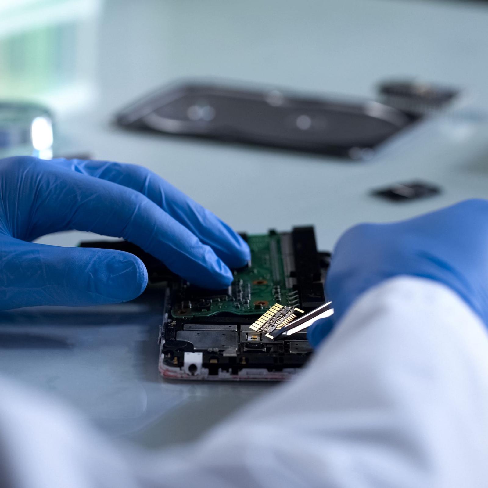 Lab technician taking components out of a cell phone.