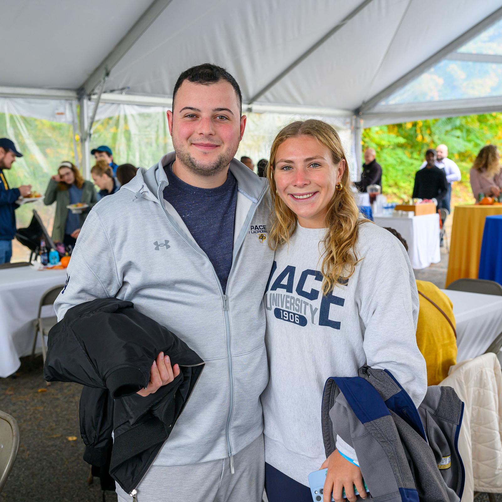 Two Pace University alumni smiling at the camera at Homecoming 2024.