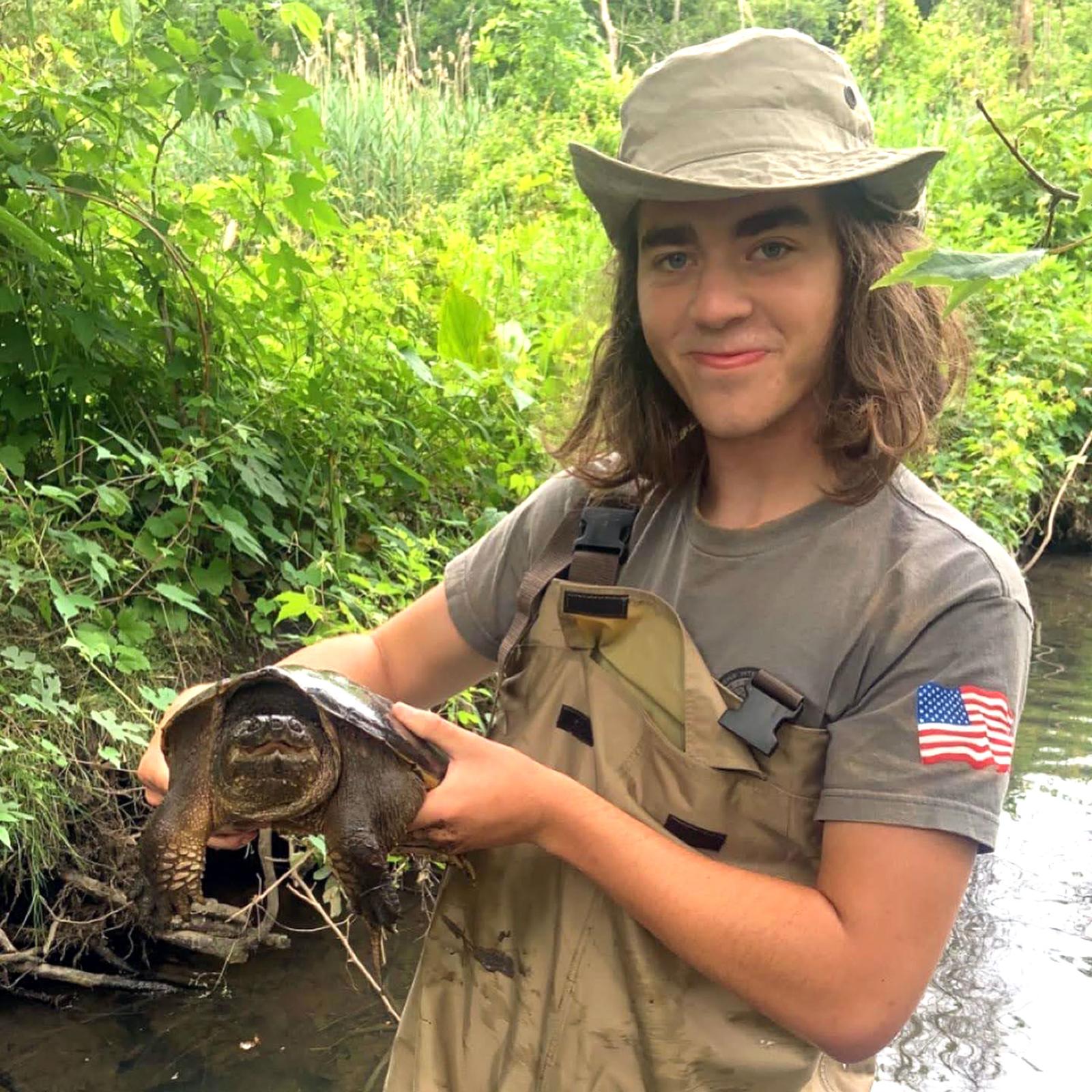 Pace University environmental studies and science student Lucas holding a large turtle
