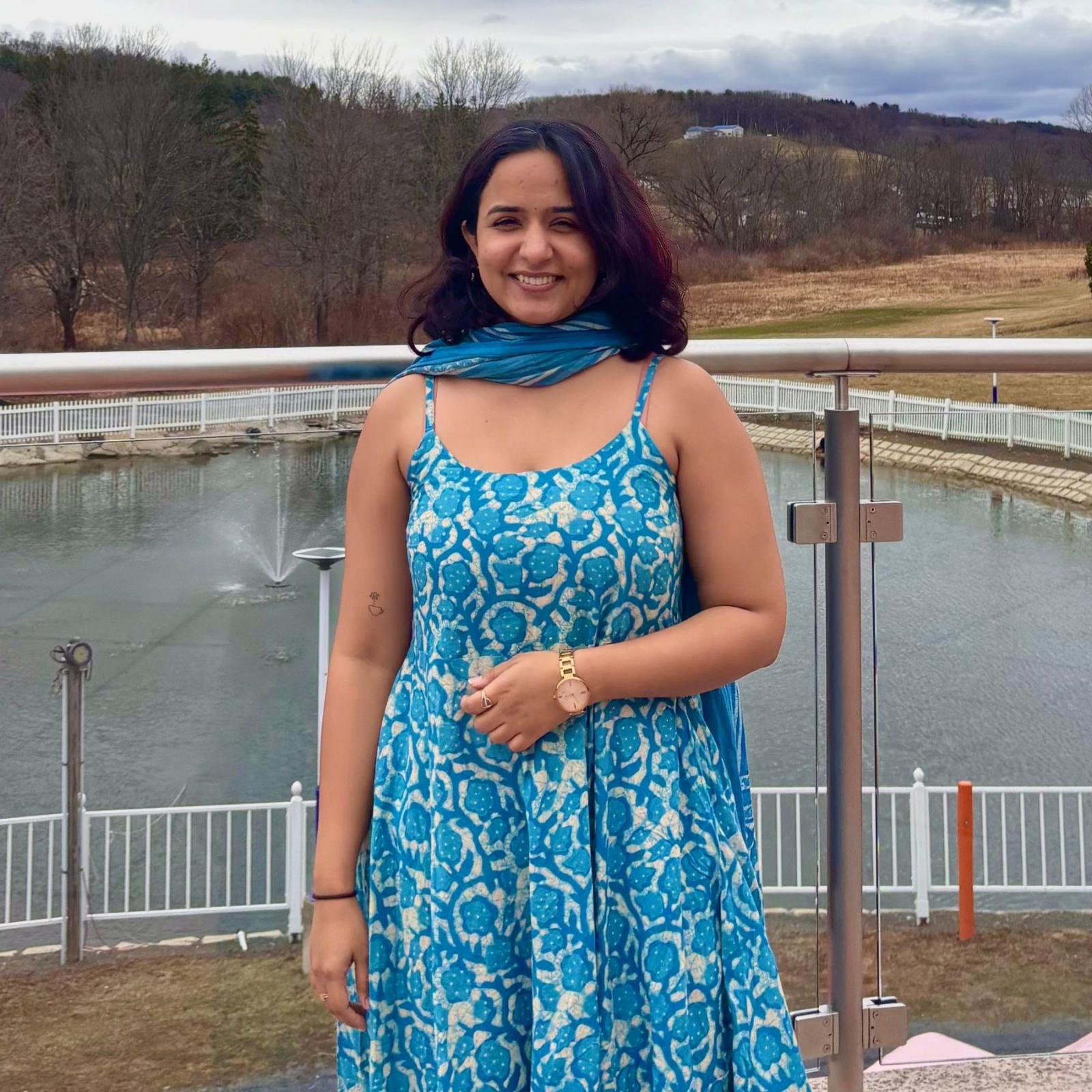 Seidenberg student Riya Golani smiling for a photo in front of a lake in nature.