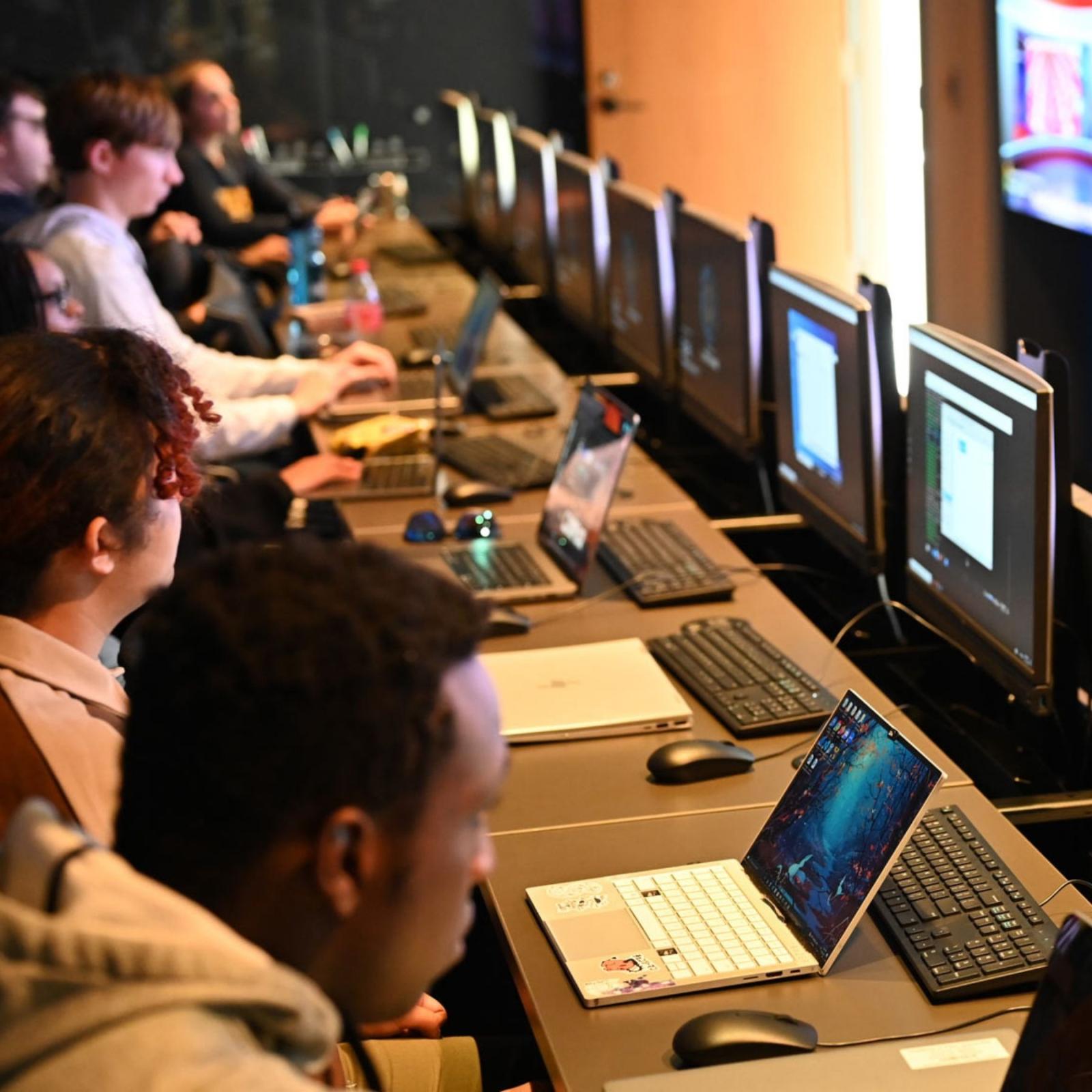 Pace students working in front of a row of computers within the Cyber Range