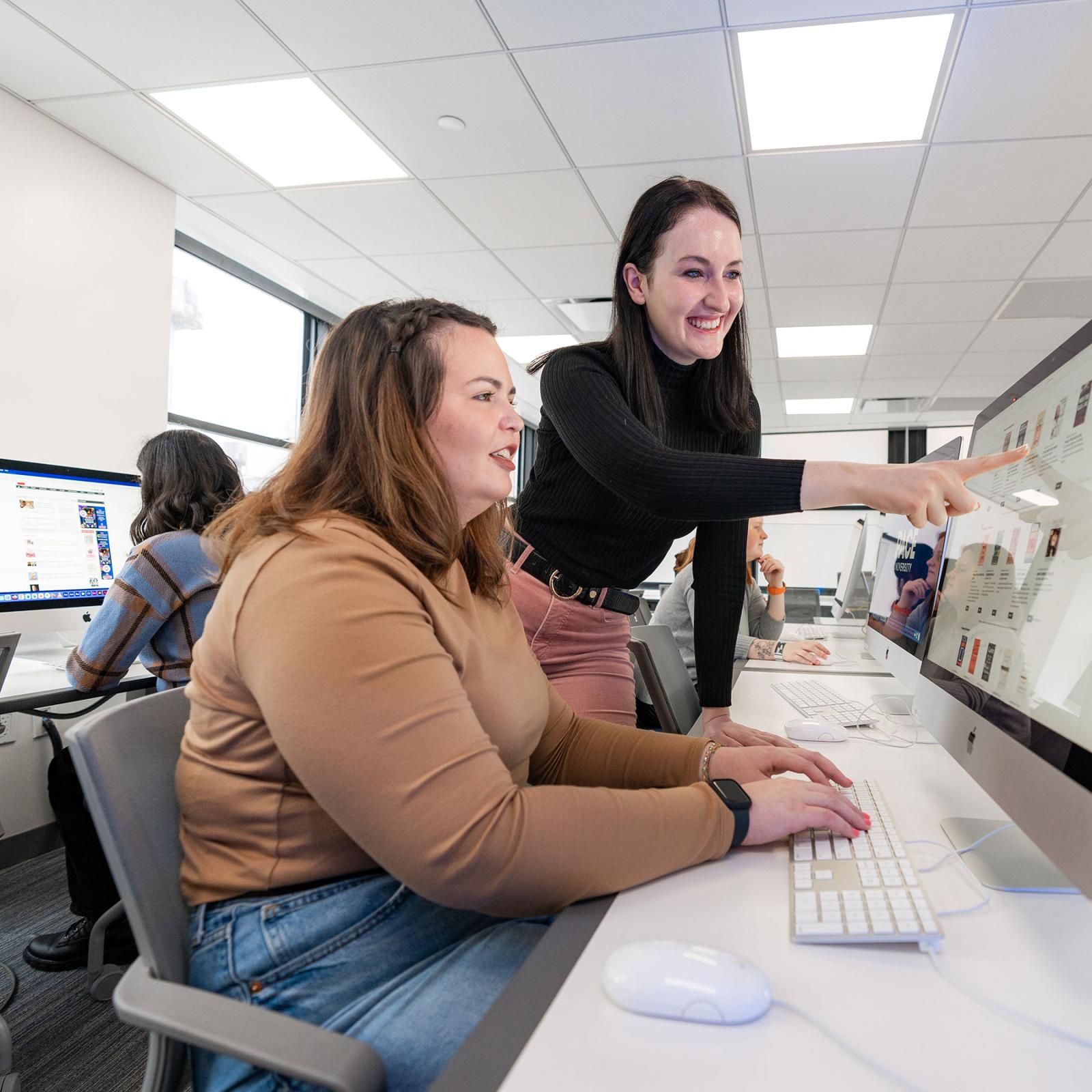 Pace University Publishing student and faculty looking at computer screen together in a computer lab