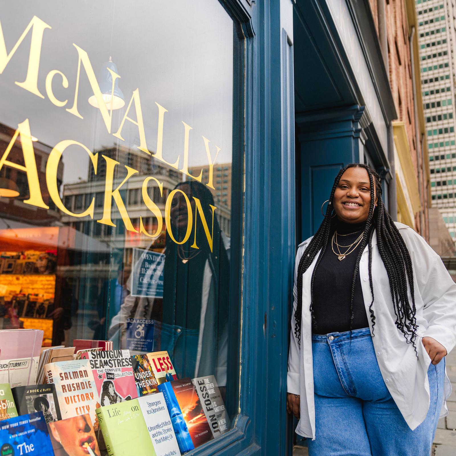 Pace University Publishing student leaning against the McNally Jackson bookstore entrance