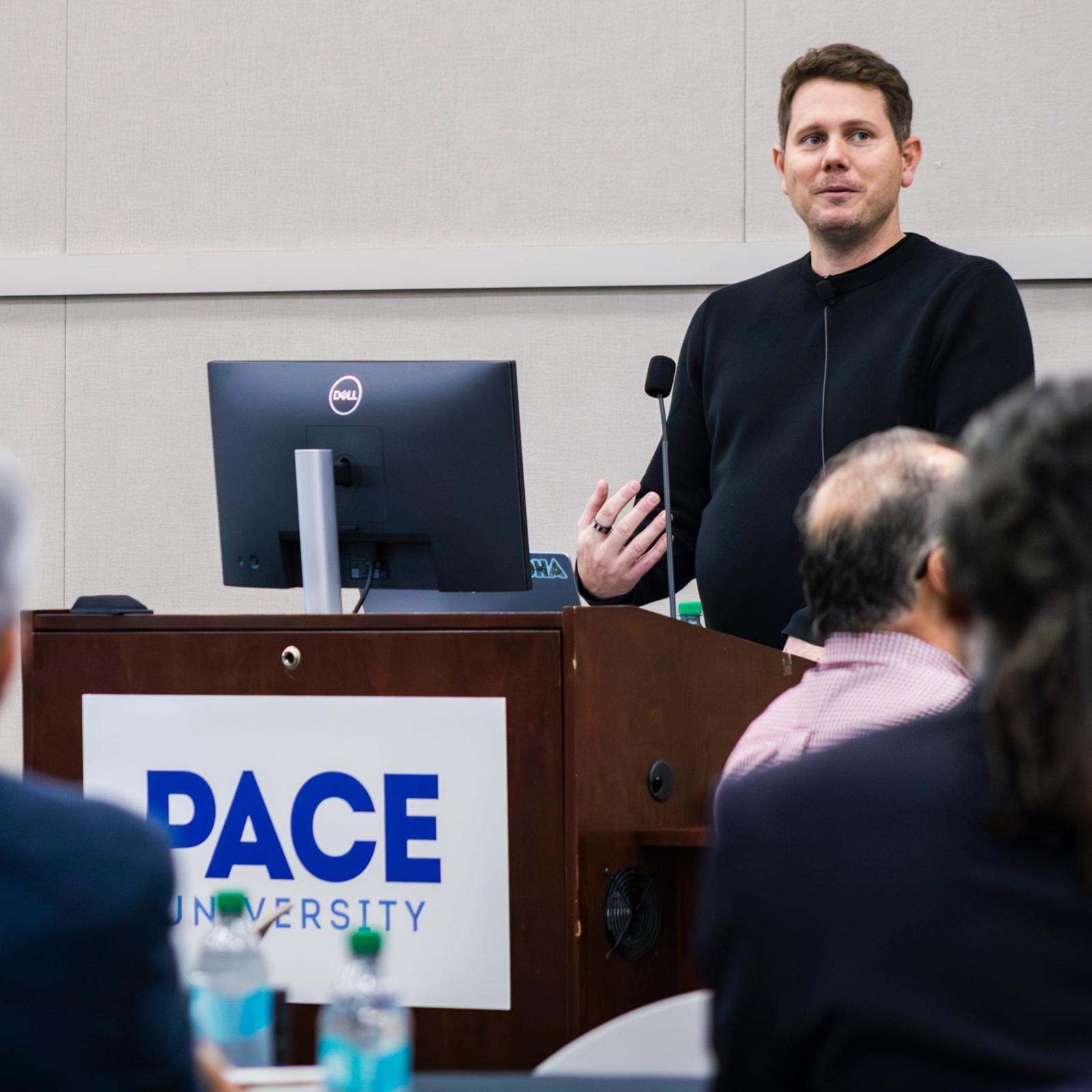 Google AI expert Charles Elliott speaks at a podium