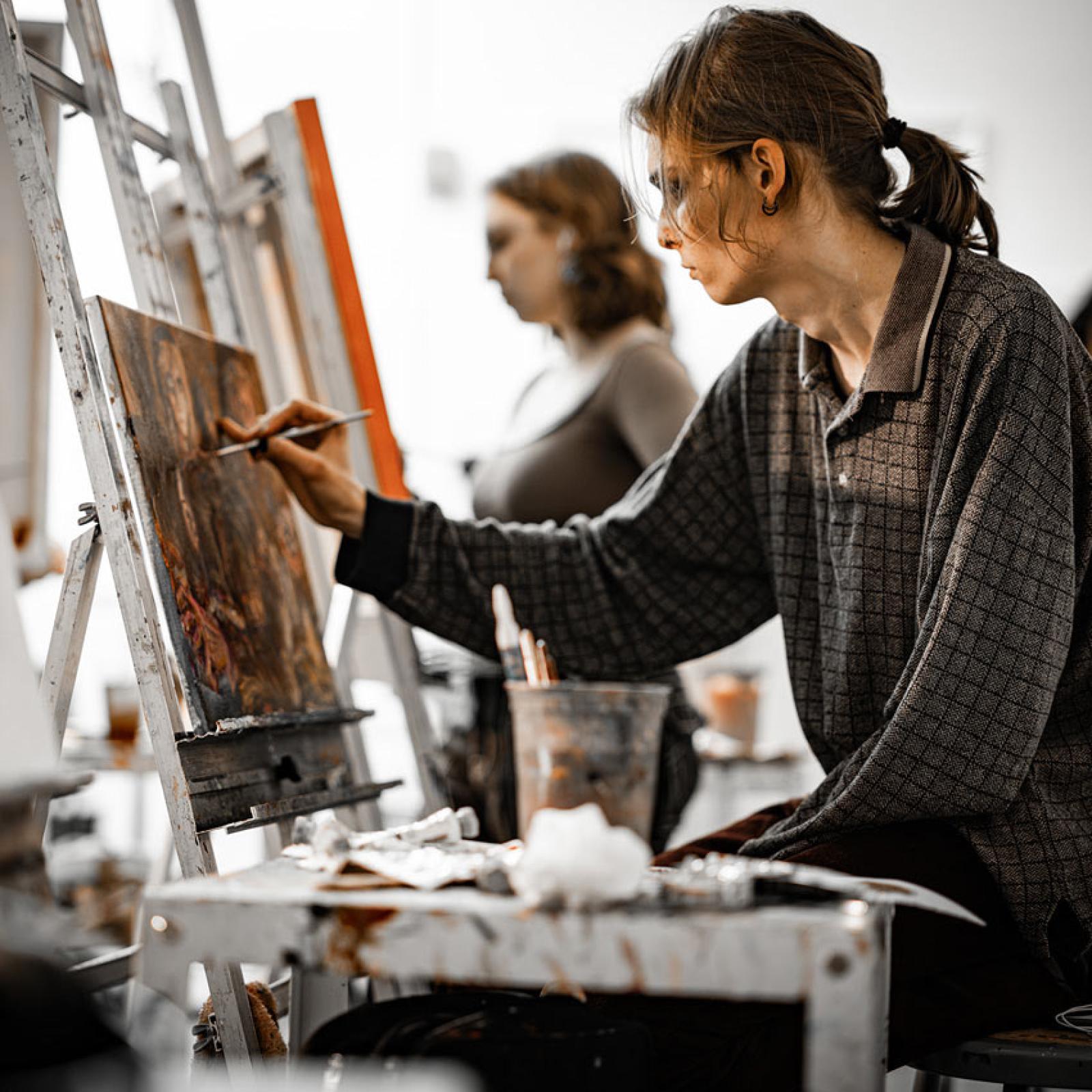 A Pace University art student painting at an easel.