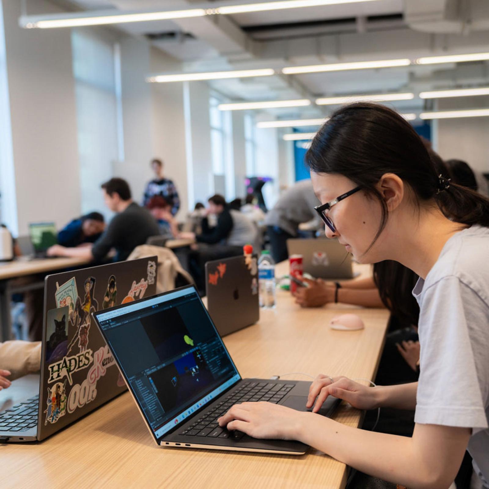 A young woman in the Seidenberg labs looking at her laptop.