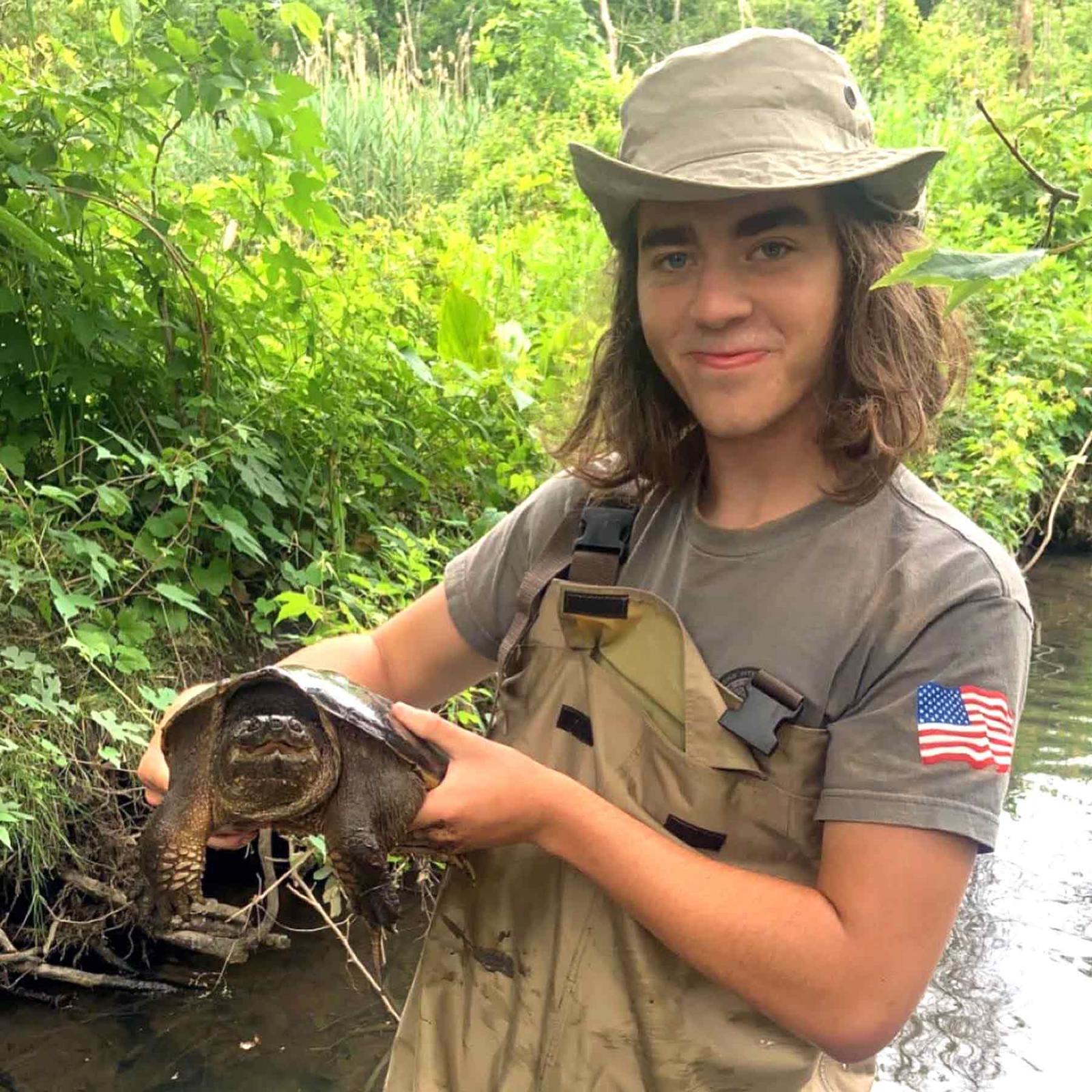 Pace University environmental studies and science student Lucas holding a large turtle