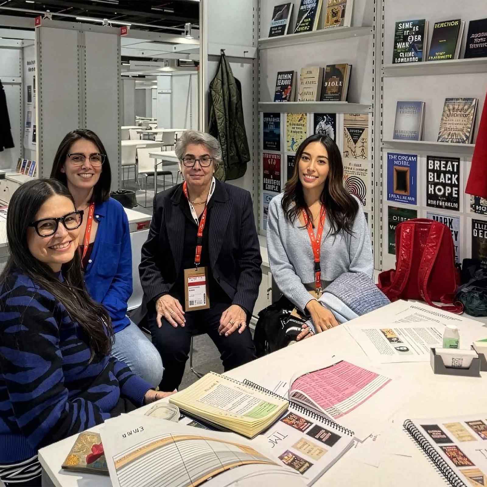 Pace University Publishing faculty and students sitting together with book publishing studio members at a table of cover samples and writing