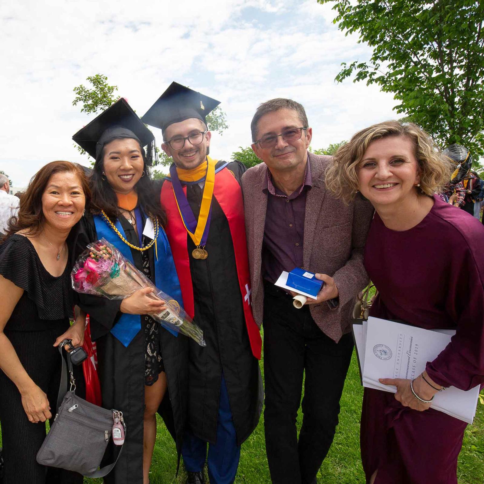 Pace student at his Commencement ceremony with his family, smiling at the camera.
