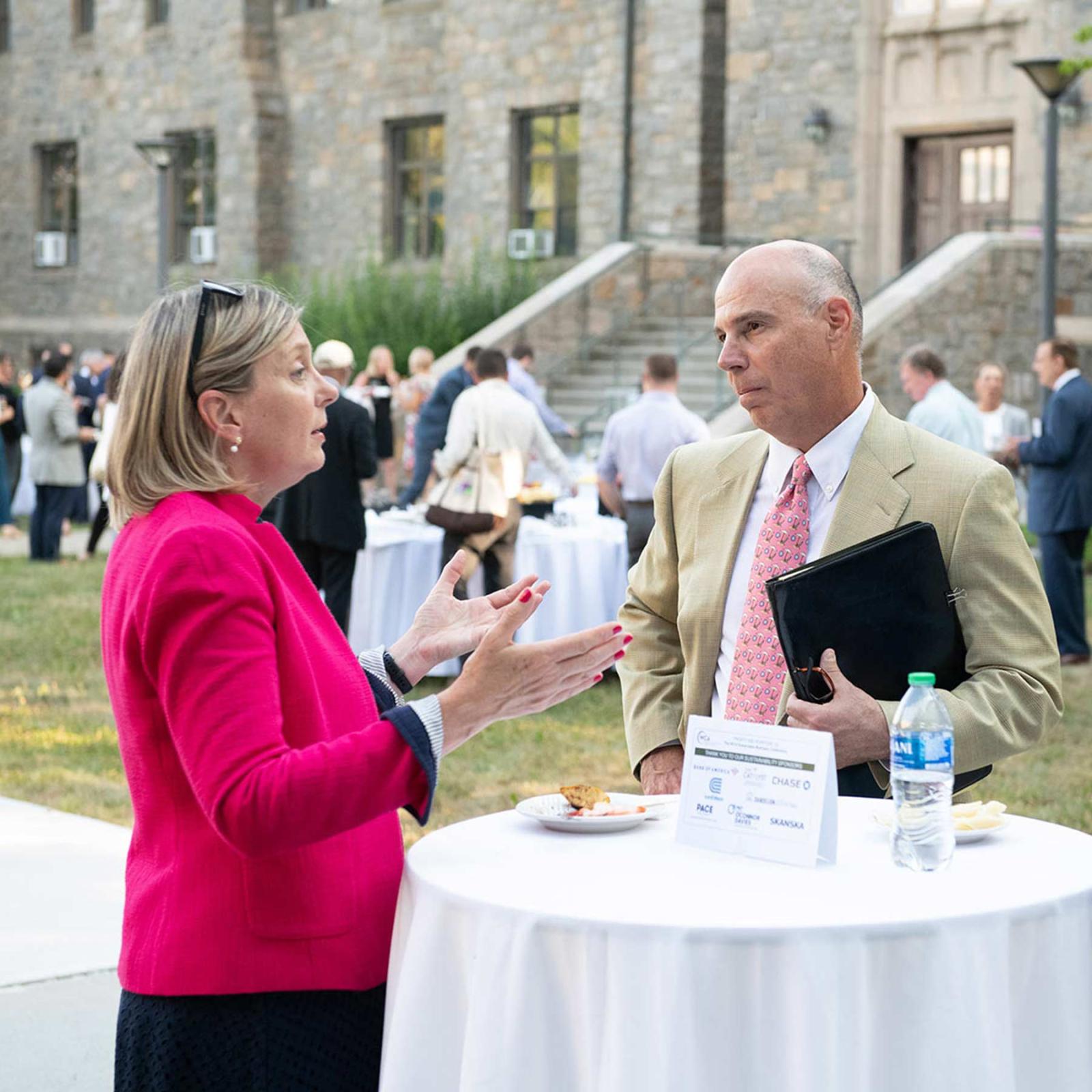 A man and woman conversing at an oustide table during an event