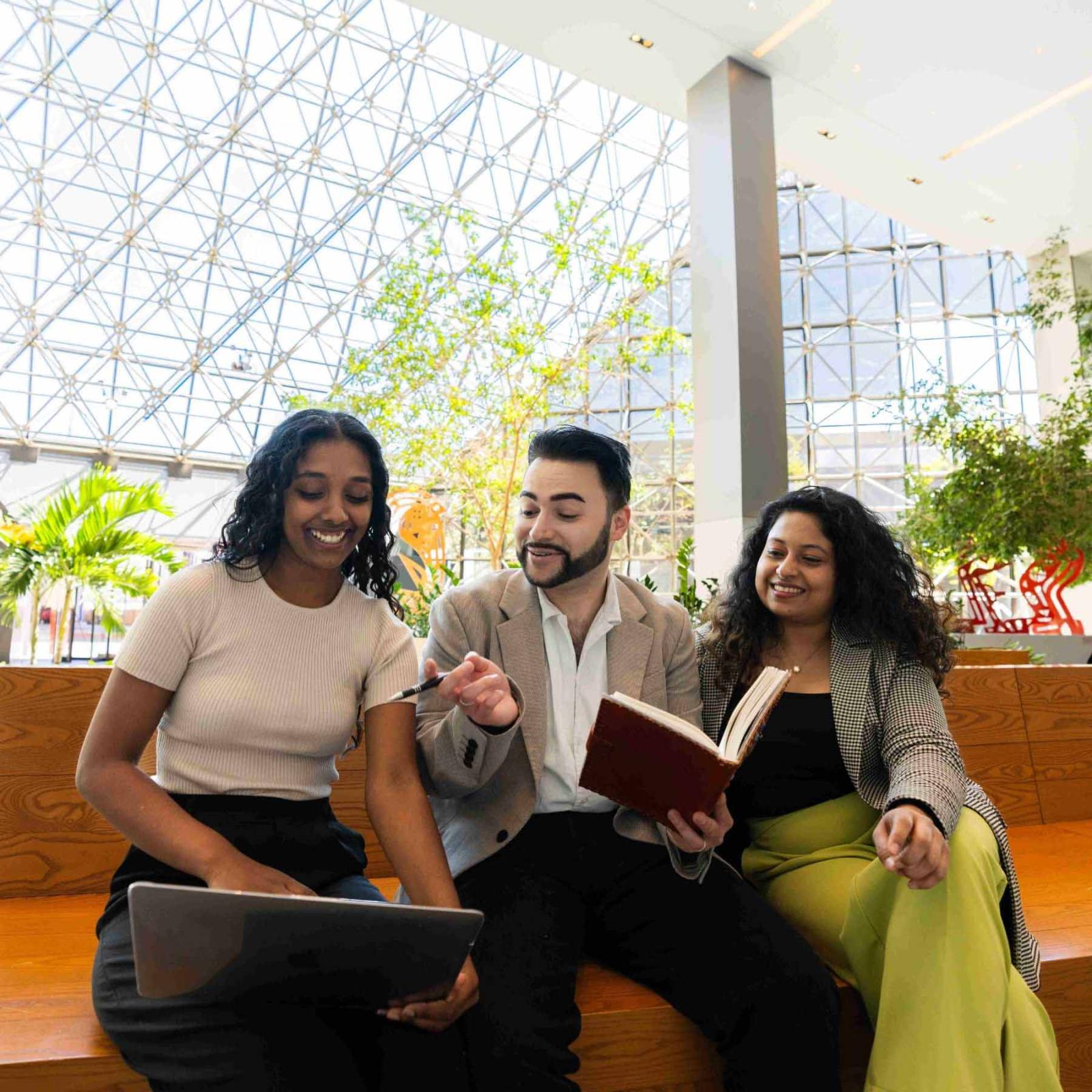 Pace students sitting on a bench in NYC and working on a laptop together.