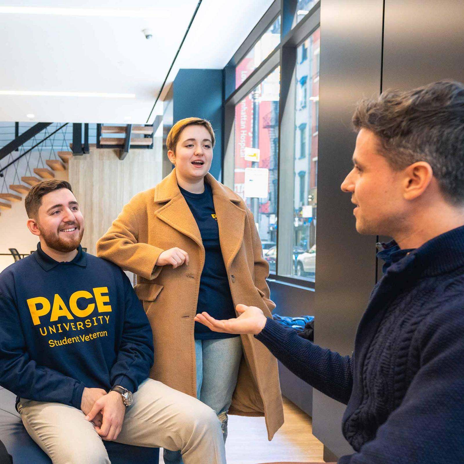 3 Pace University students laughing together in a student lounge on the New York City Campus.