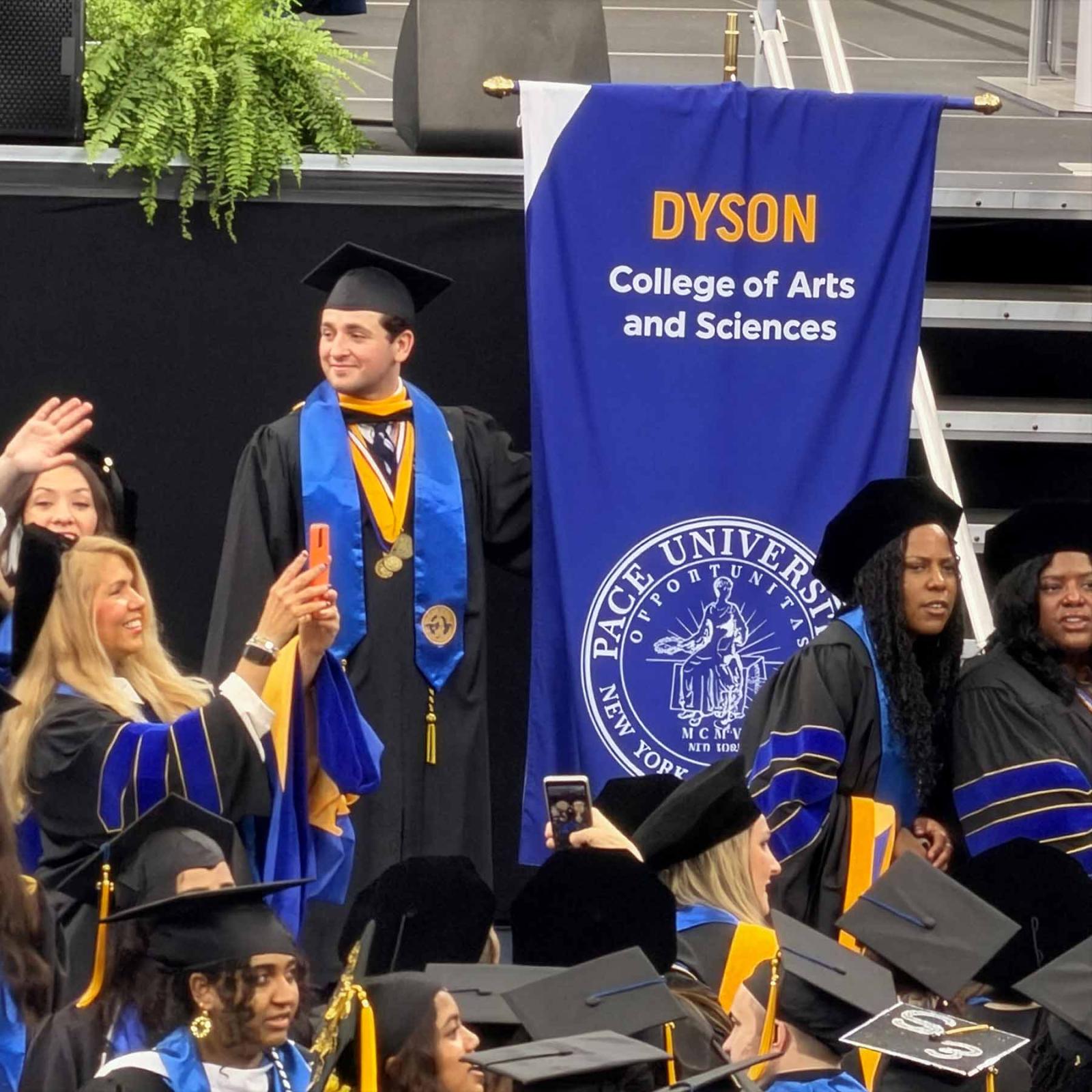 Pace University Economics student carrying the Dyson College banner at commencement