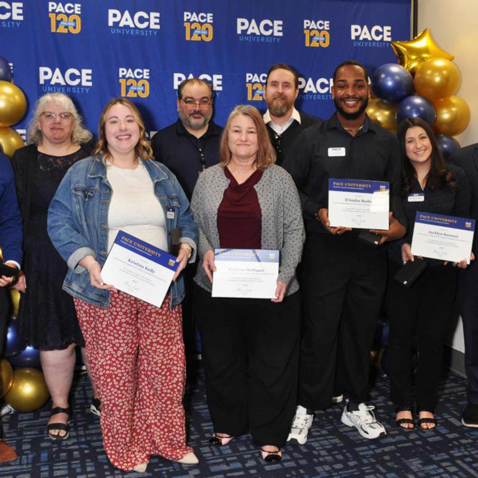 Group of Pace University employees smiling at the camera after winning recognition awards.