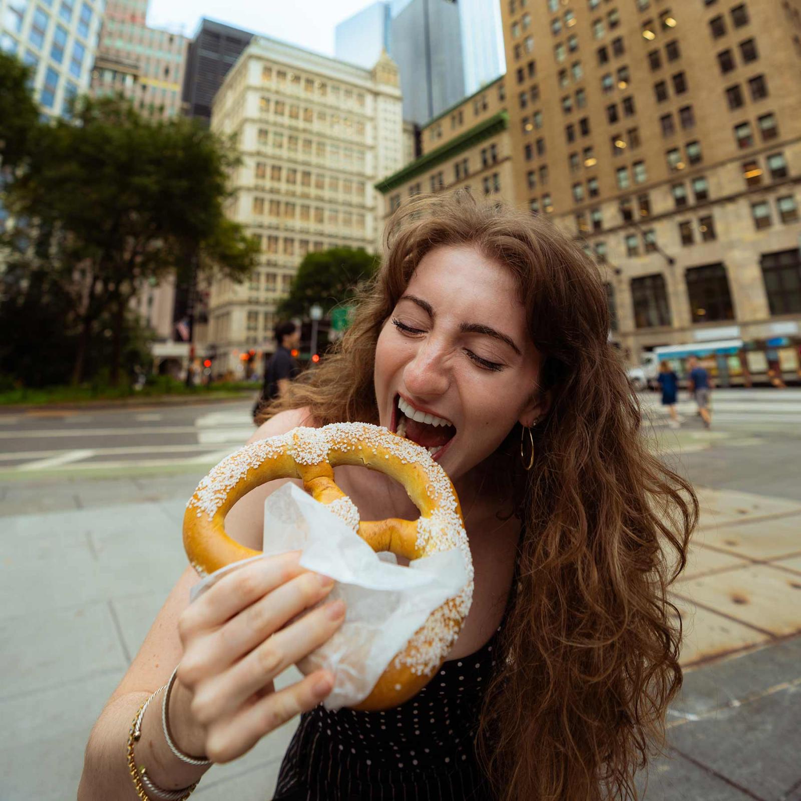 Pace University student in NYC eating a pretzel.