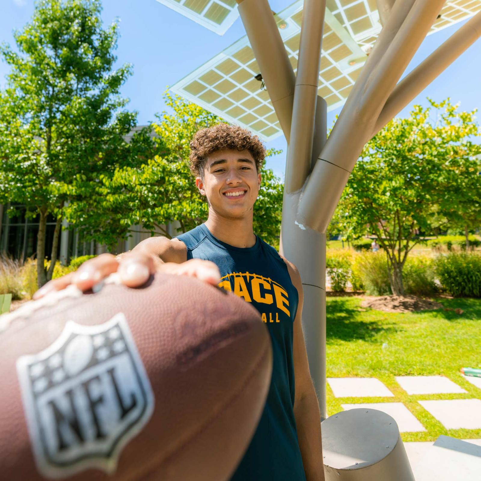 Pace University athlete, smiling at the camera, holding a football.