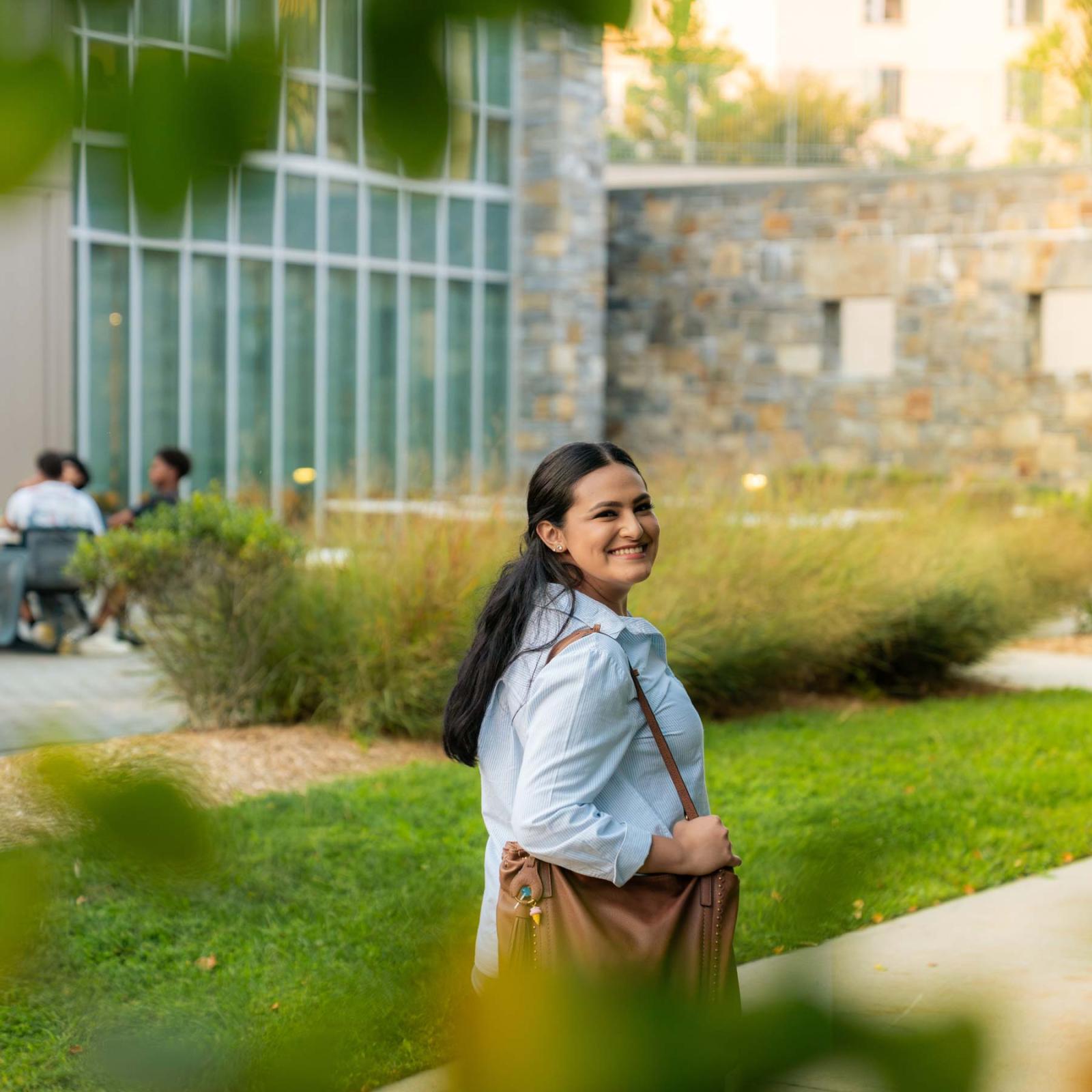 Pace University student walking around the Westchester campus, smiling at the camera.