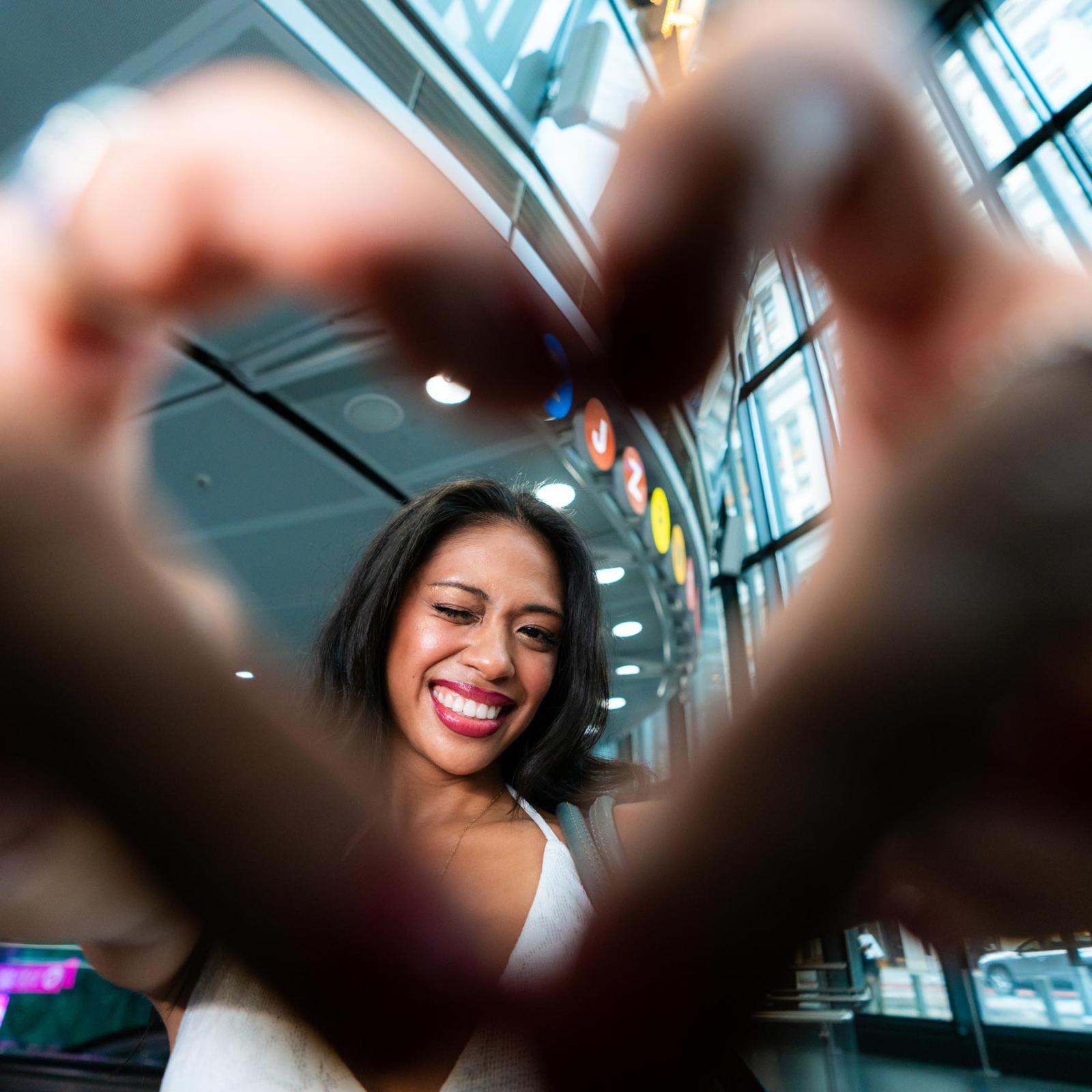 Pace University student making a heart with her fingers and looking through it.
