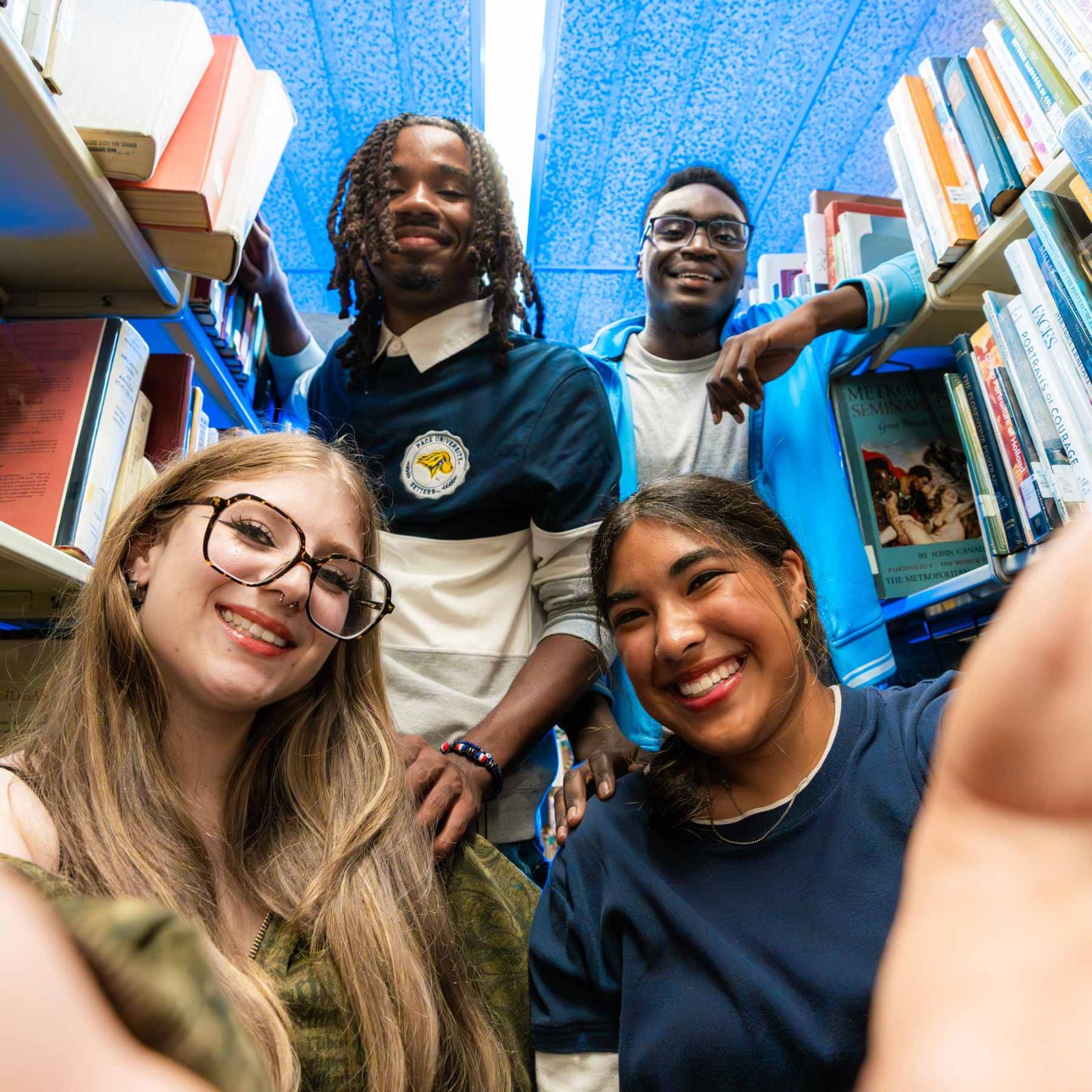 Group of Pace University students in the library smiling at the camera.