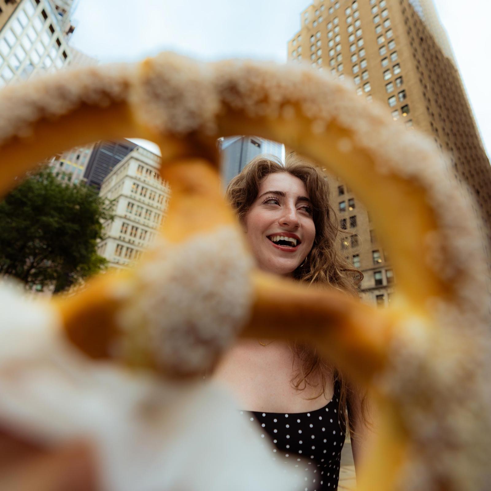 Pace University student looking through a NYC pretzel, smiling.