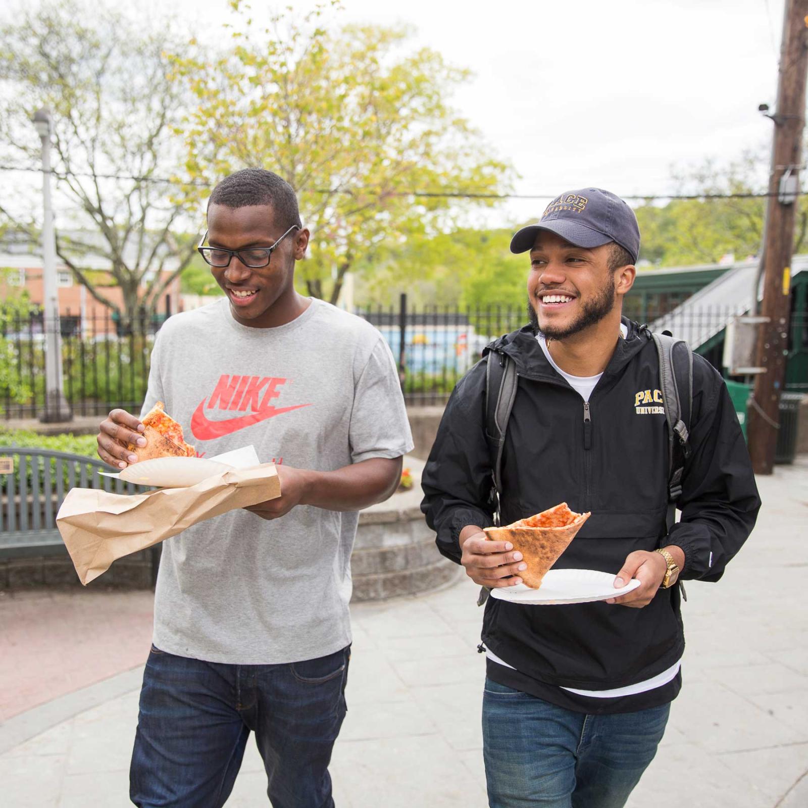 Two Pace University students eating pizza.
