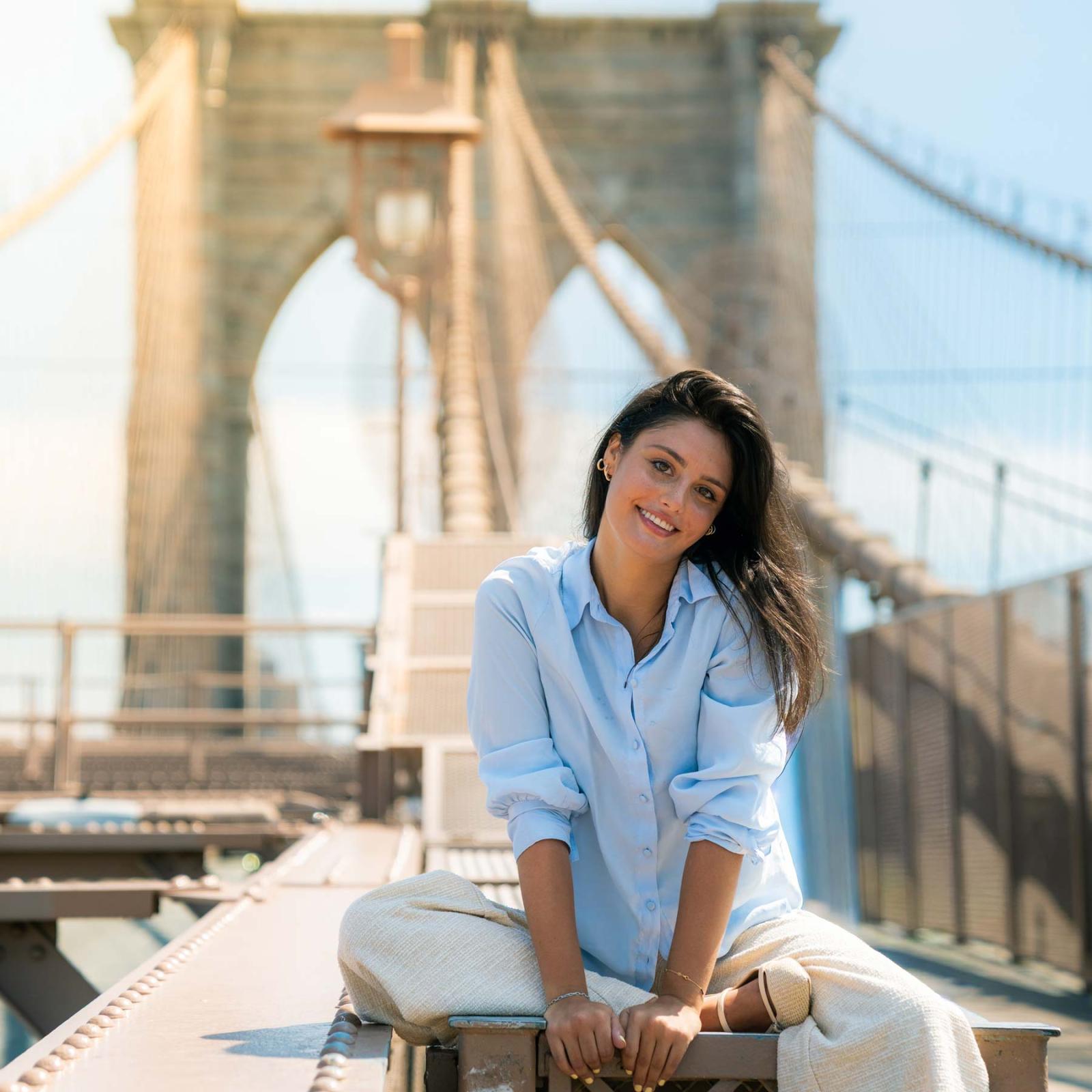 Pace University student sitting on the Brooklyn Bridge in NYC.