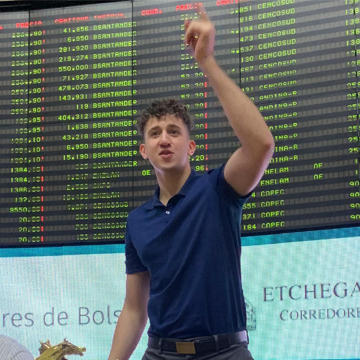 Pace alumnus Ruben Irizarry wearing a blue shirt in front of a stock ticker board