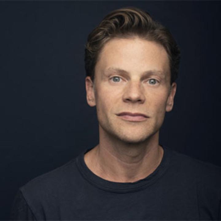Portrait of Brian Letendre wearing a black shirt with a black background