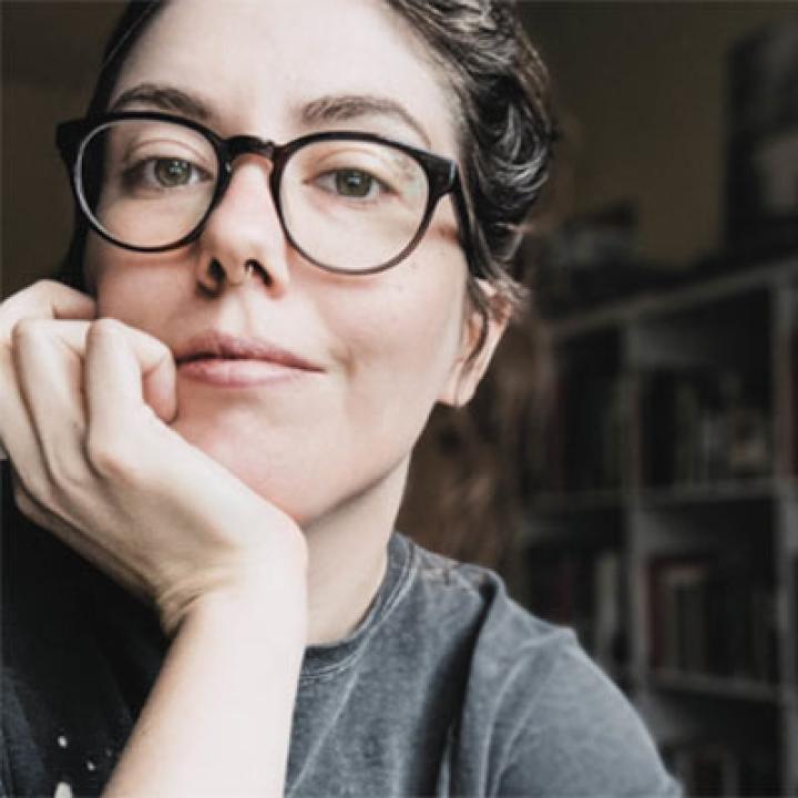 Portrait of Emily Gillespie wearing glasses and with her head resting on her hand