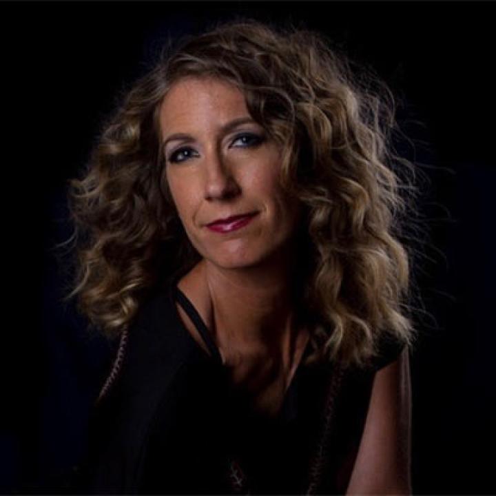 Portrait of Shelly Hutchinson wearing a black blouse with a black background