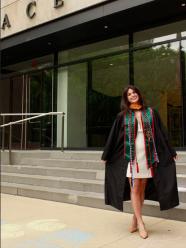 Alessandra Barretta '26 posing in her cap and gown in front of One Pace Plaza.